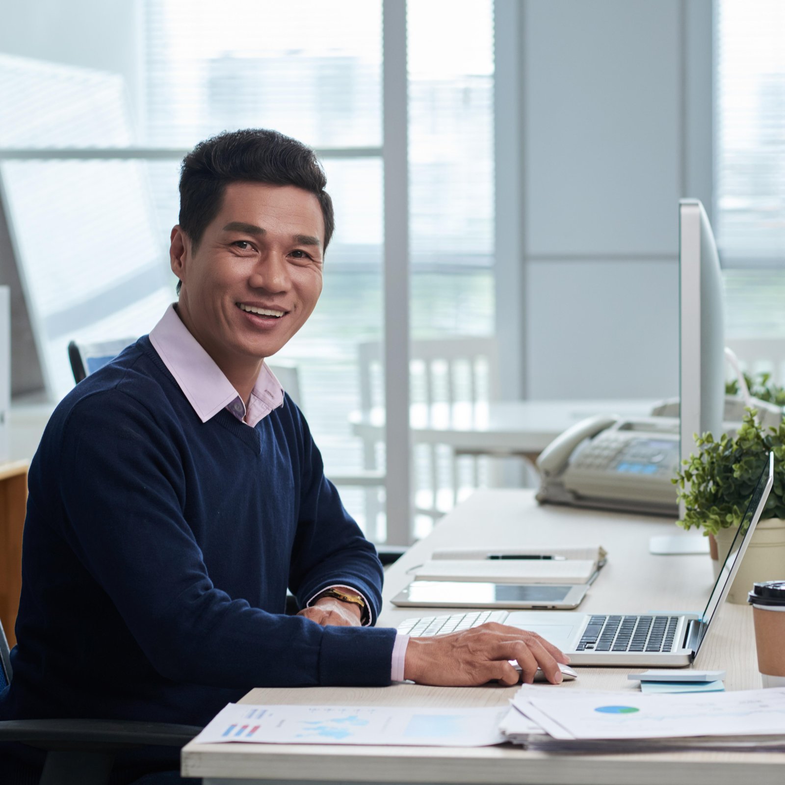 banner/smiling-vietnamese-businessman-sitting-desk-office-looking-camera.jpg